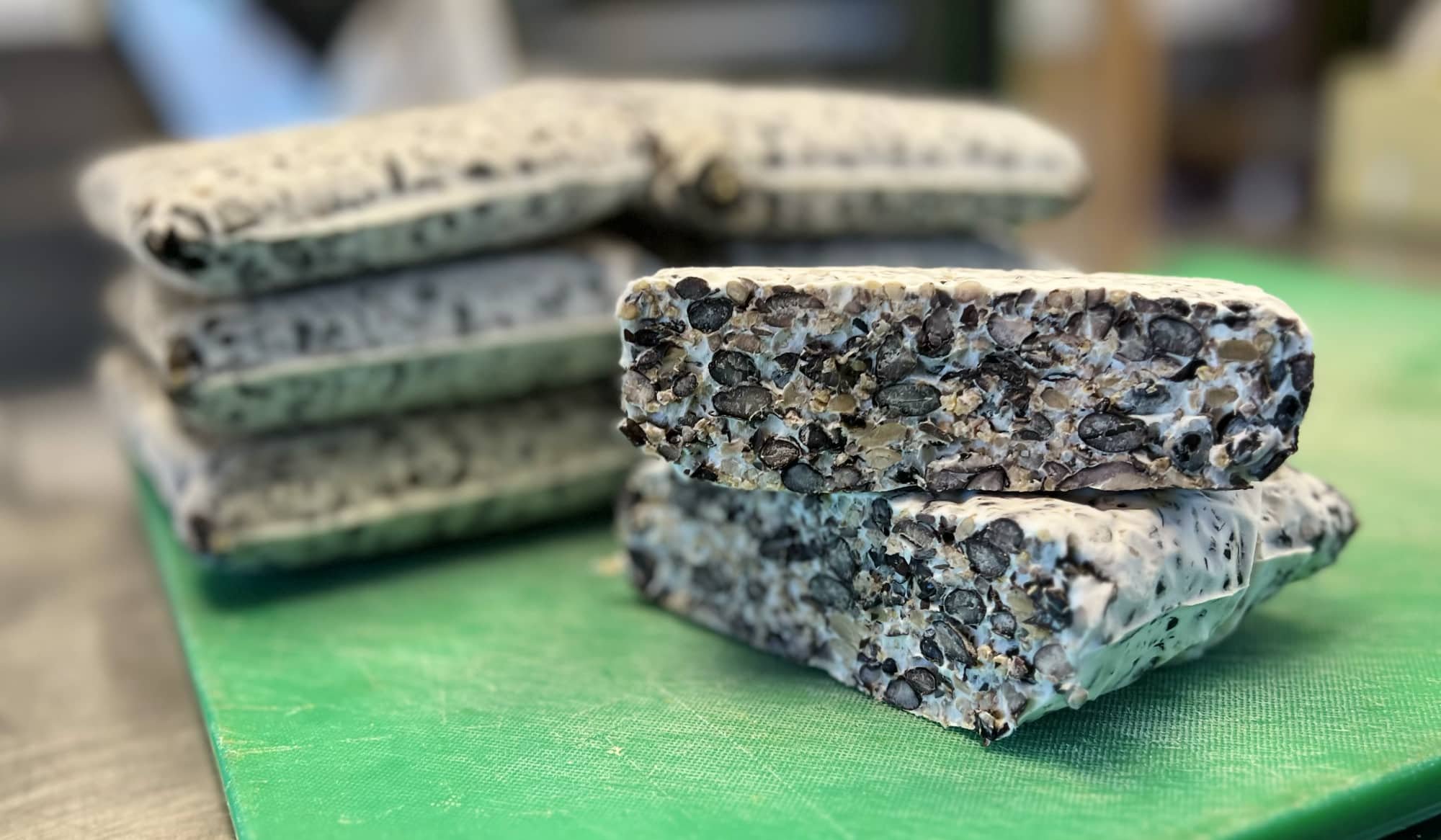 stacks of black beauty black bean tempeh on a green cutting board.