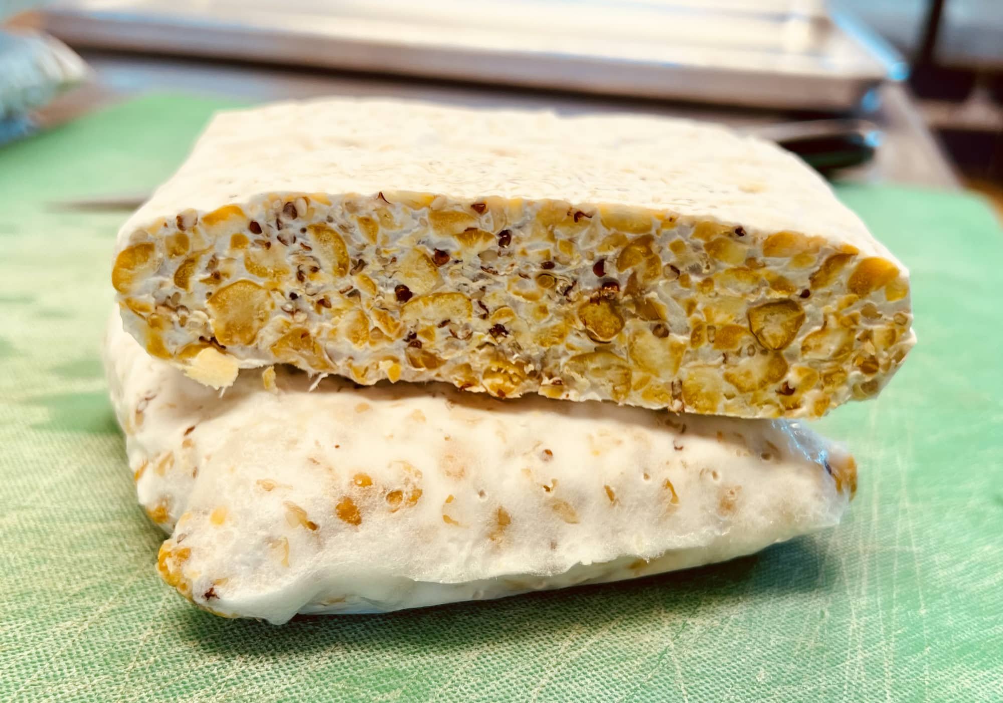 two pieces of sesame delightful chickpea tempeh on a cutting board.