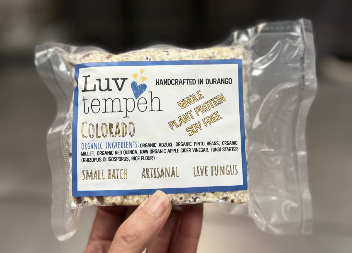 a hand holding a package of frozen colorado tempeh.