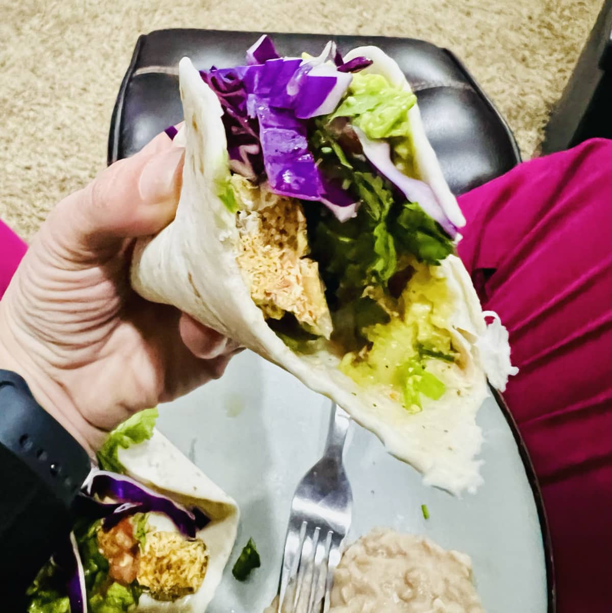 a hand holding a baja style tempeh taco with a bite taken out of it.