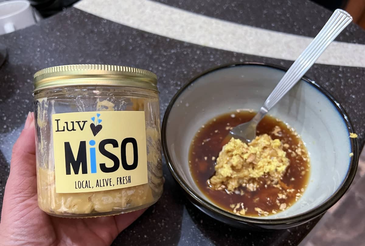 a jar of red lentil miso next to a bowl with ginger miso dressing ingredients.