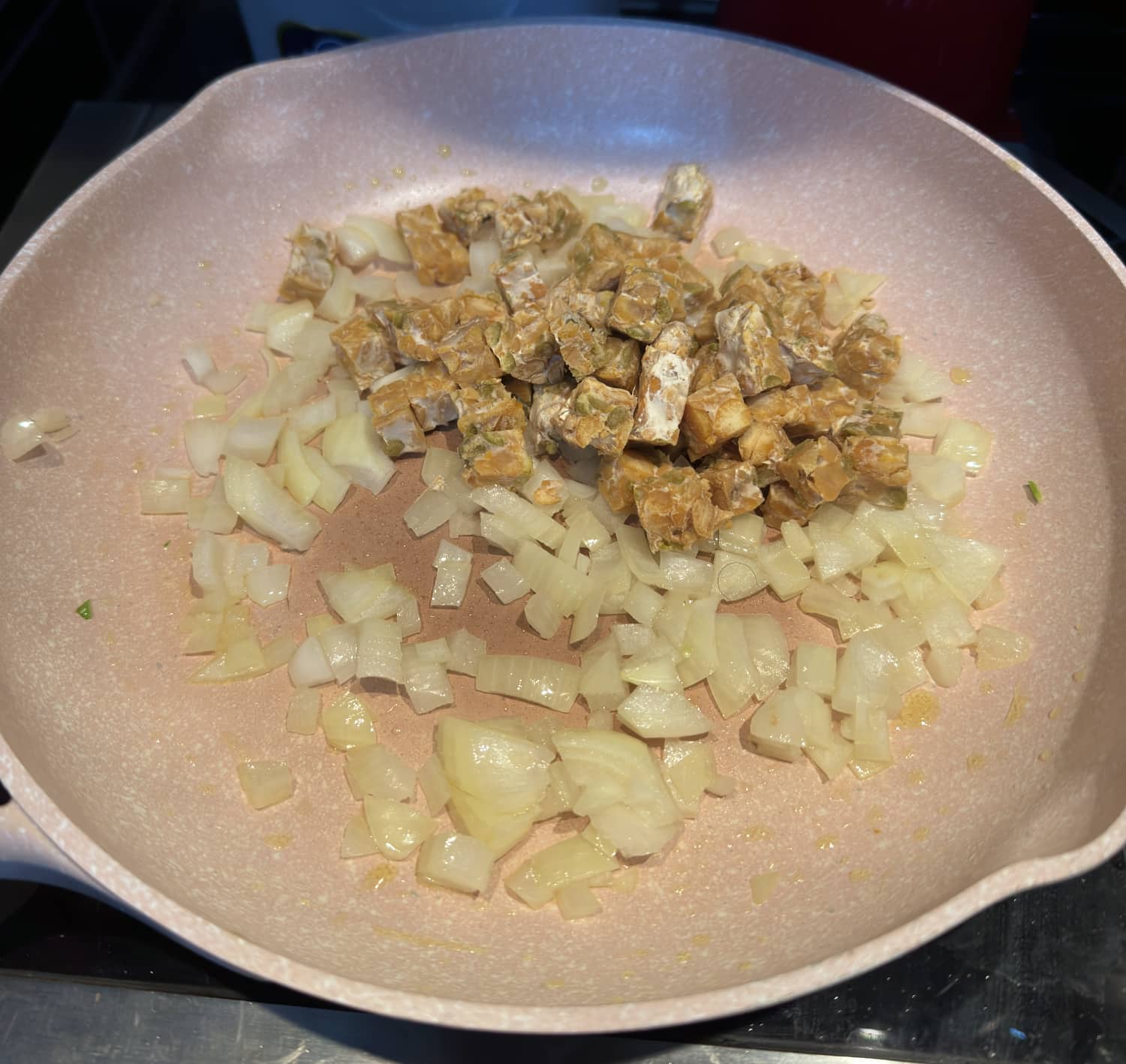 onions and tempeh cooking in a skillet.