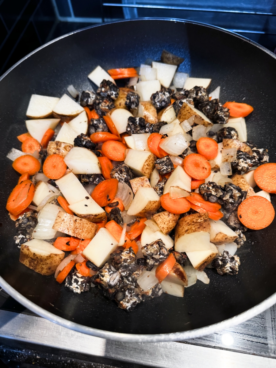 carrots and potatoes added to onions and tempeh in pan.