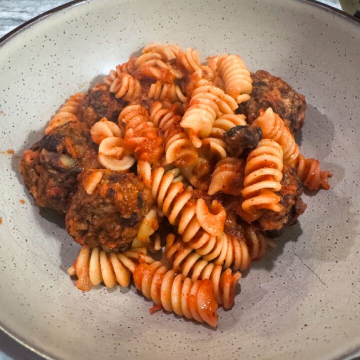 a plate with tempeh meatballs, pasta, and red sauce.