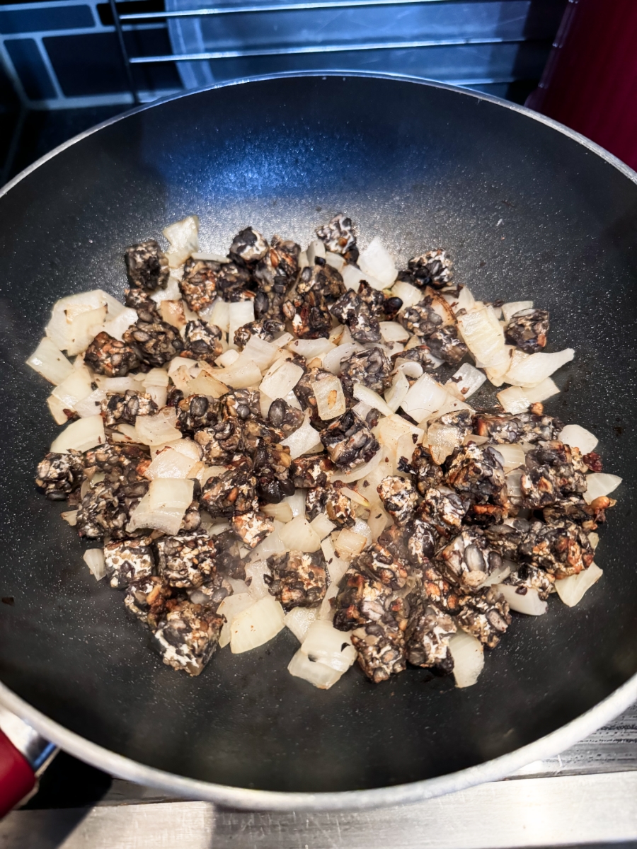 black bean tempeh and onions in a frying pan.