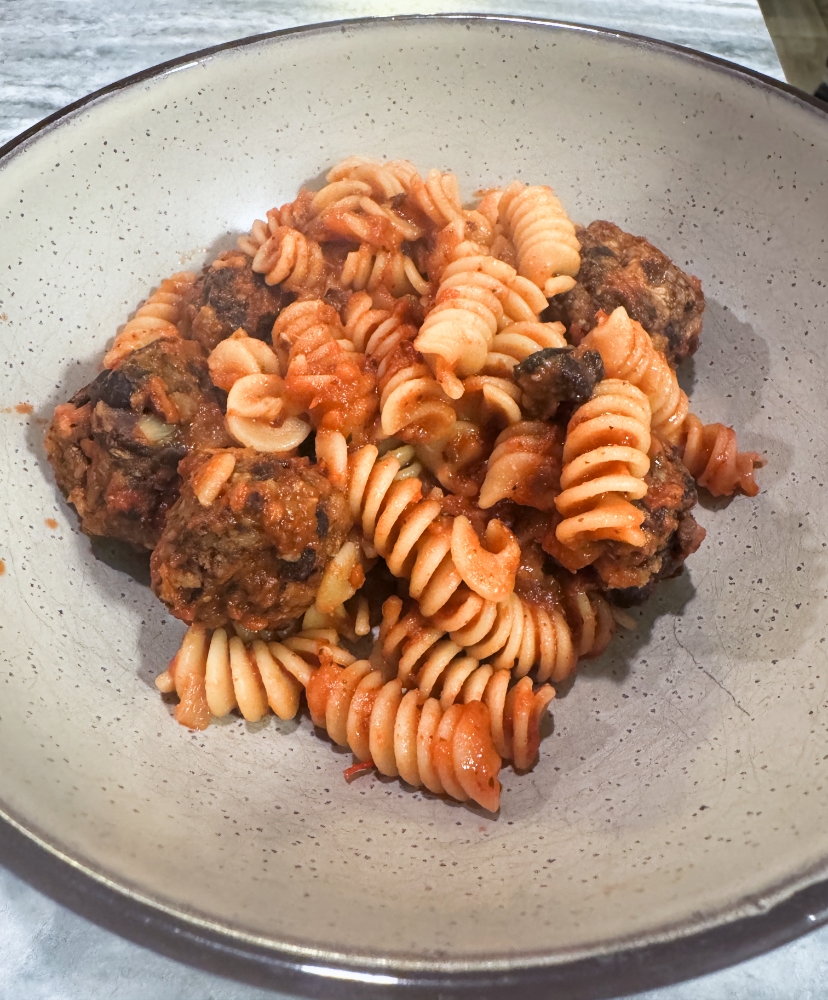 tempeh meatballs with pasta in marinara on a beige plate.