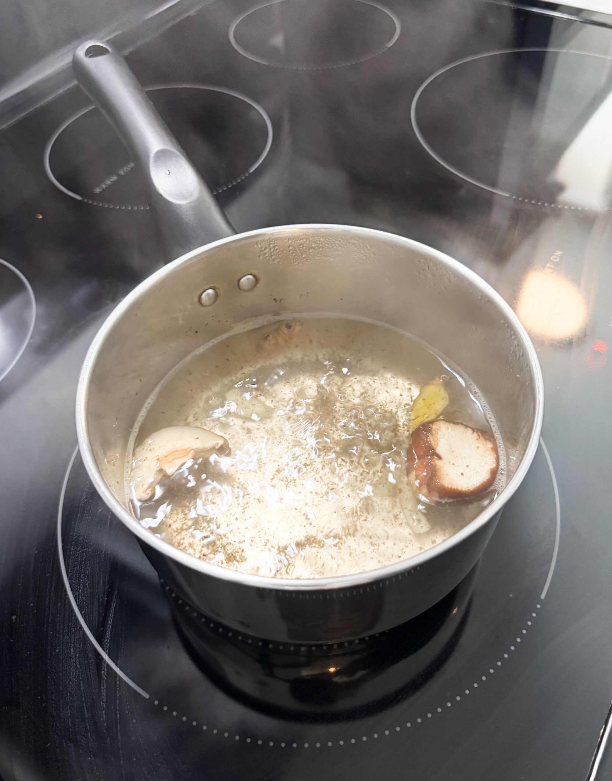 ingredients for miso sipping broth in a small pot on a stove boiling.