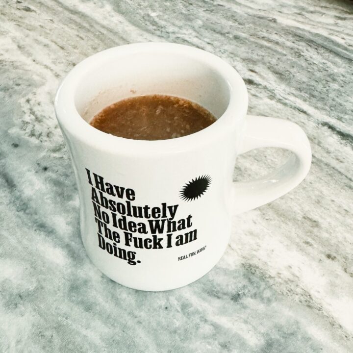 a white cup on a marble patterned counter filled with miso sipping broth.