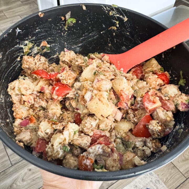 completed chickpea tempeh chaat in a black bowl with a red spoon.