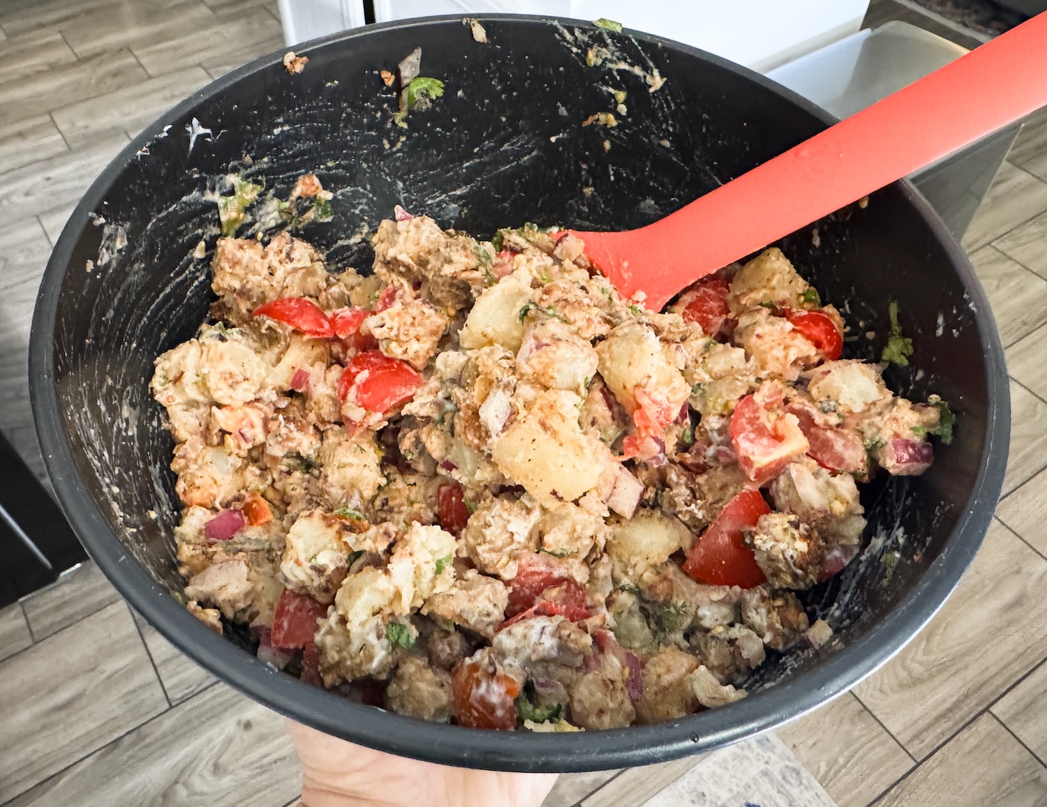 completed chickpea tempeh chaat in a black bowl with a red spoon.