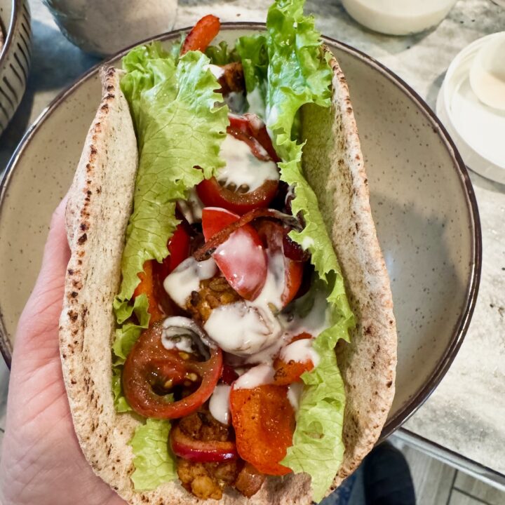 a hand holding a tempeh shawarma pita.