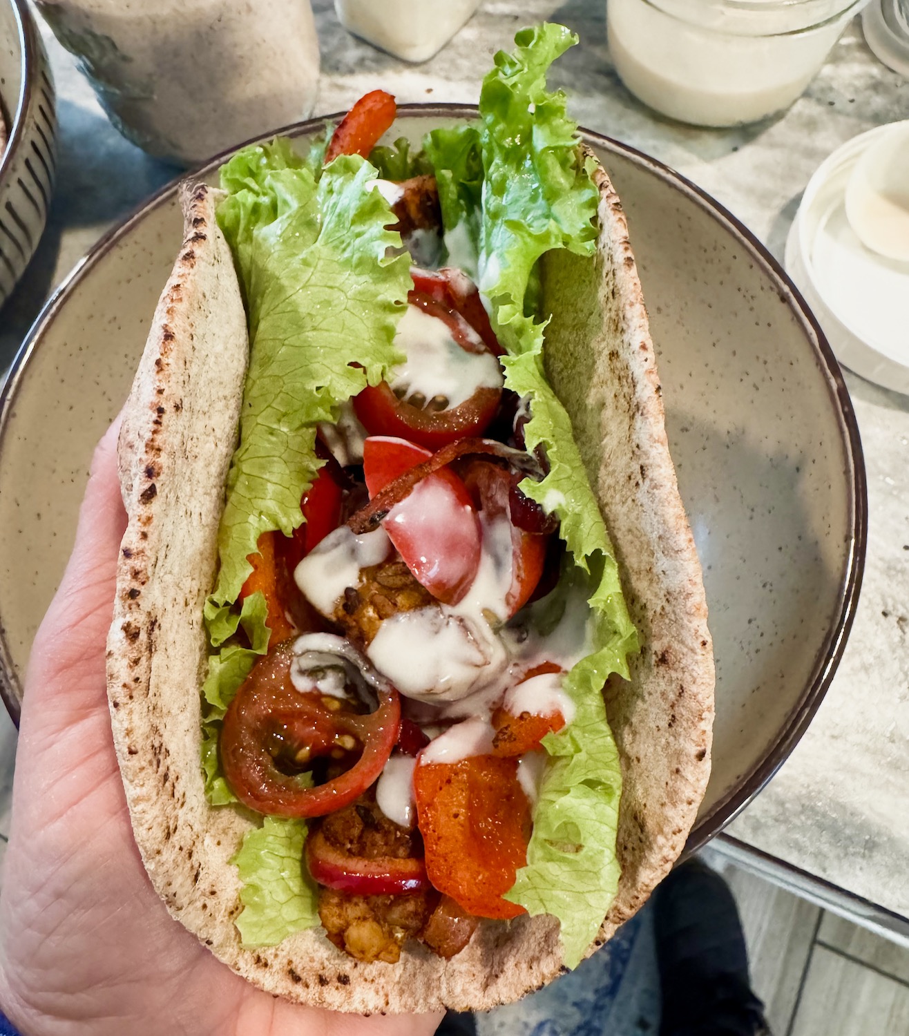 a hand holding a tempeh shawarma pita.